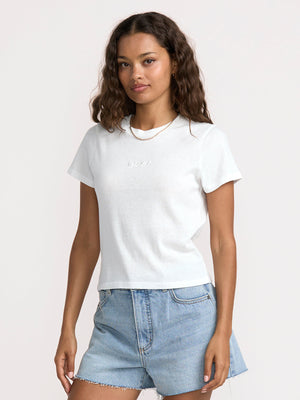 Woman wearing a white t-shirt and denim shorts on a plain background